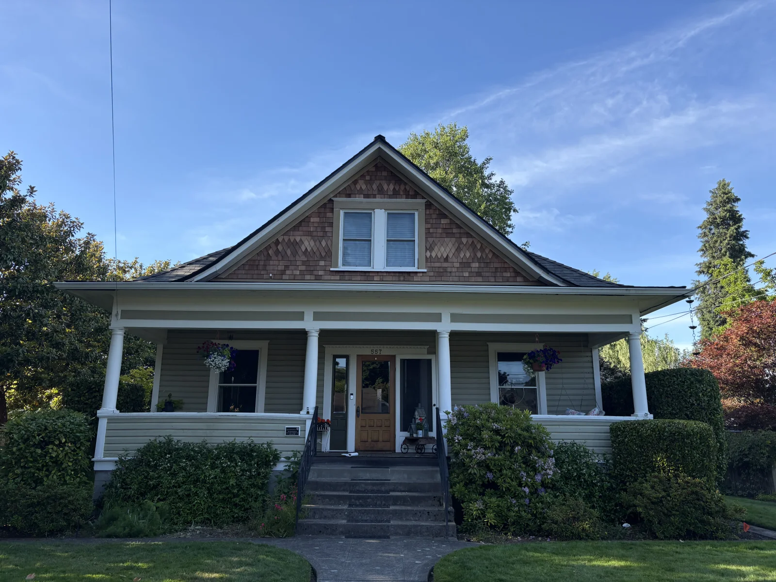 Craftsman home exterior with cedar shingle gable, white porch columns, sage lap siding, and wood front door